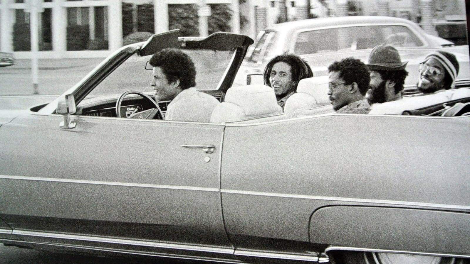 Bob Marley et ses amis souriants, voyageant en voiture.