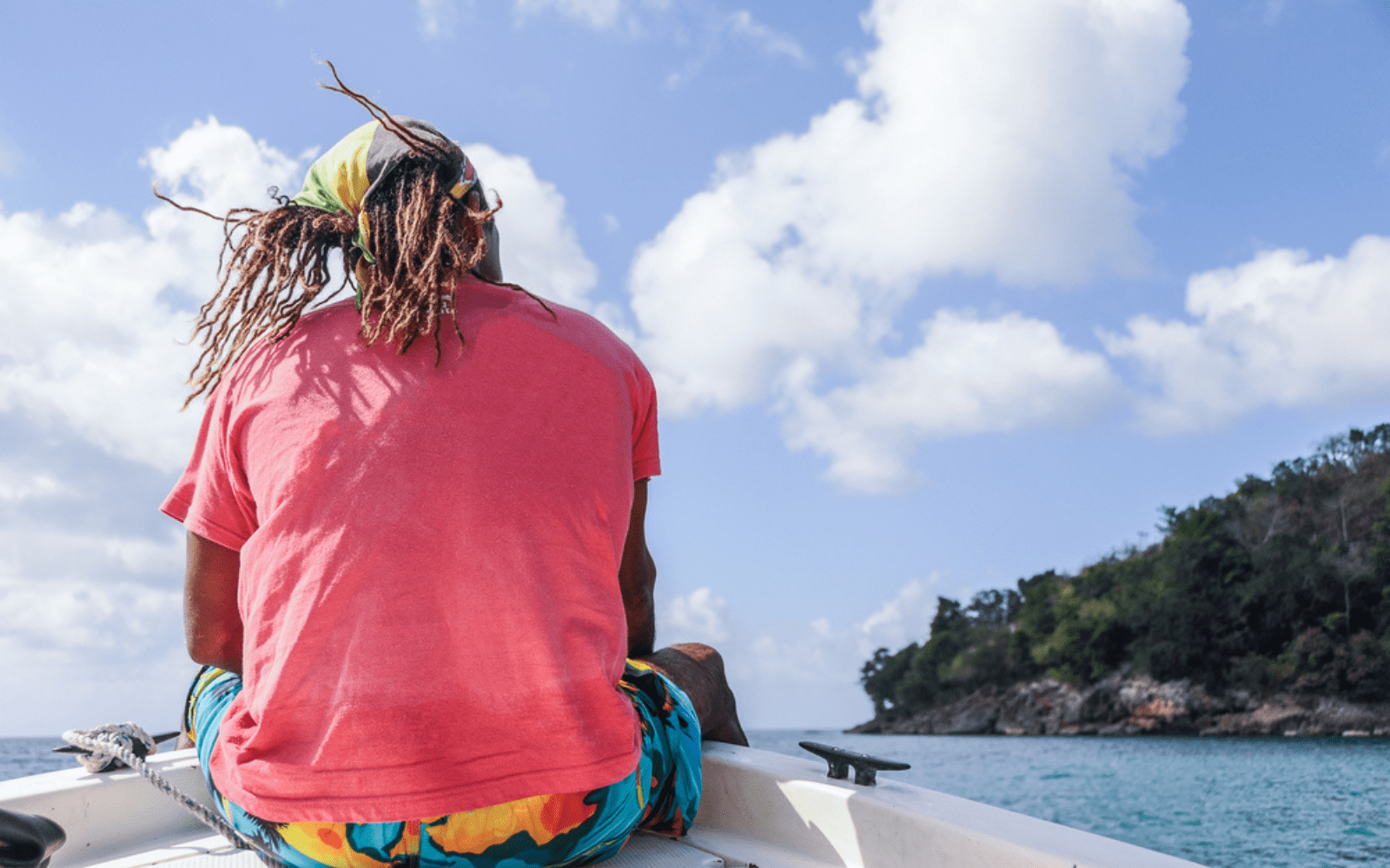 Jeune rasta de dos dreadlocks dans le vent, assis à la pointe d'une bateau