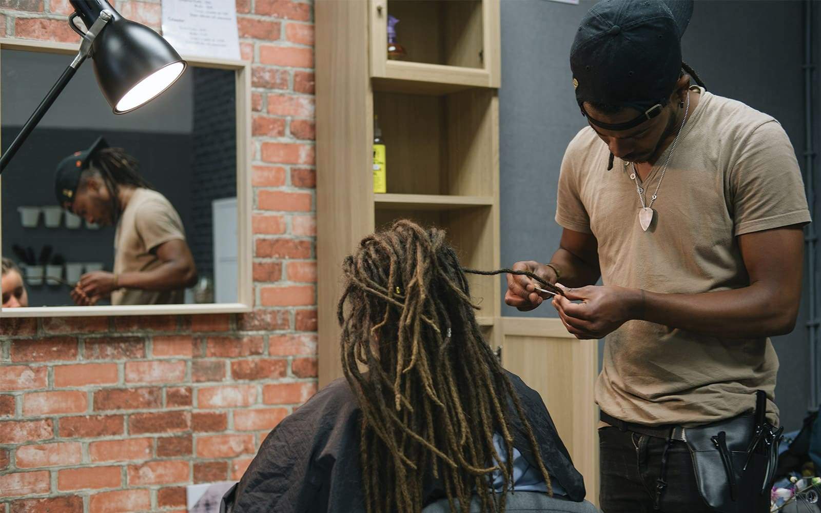 Homme faisant des dreadlocks pour jeune femme dans salon coiffure
