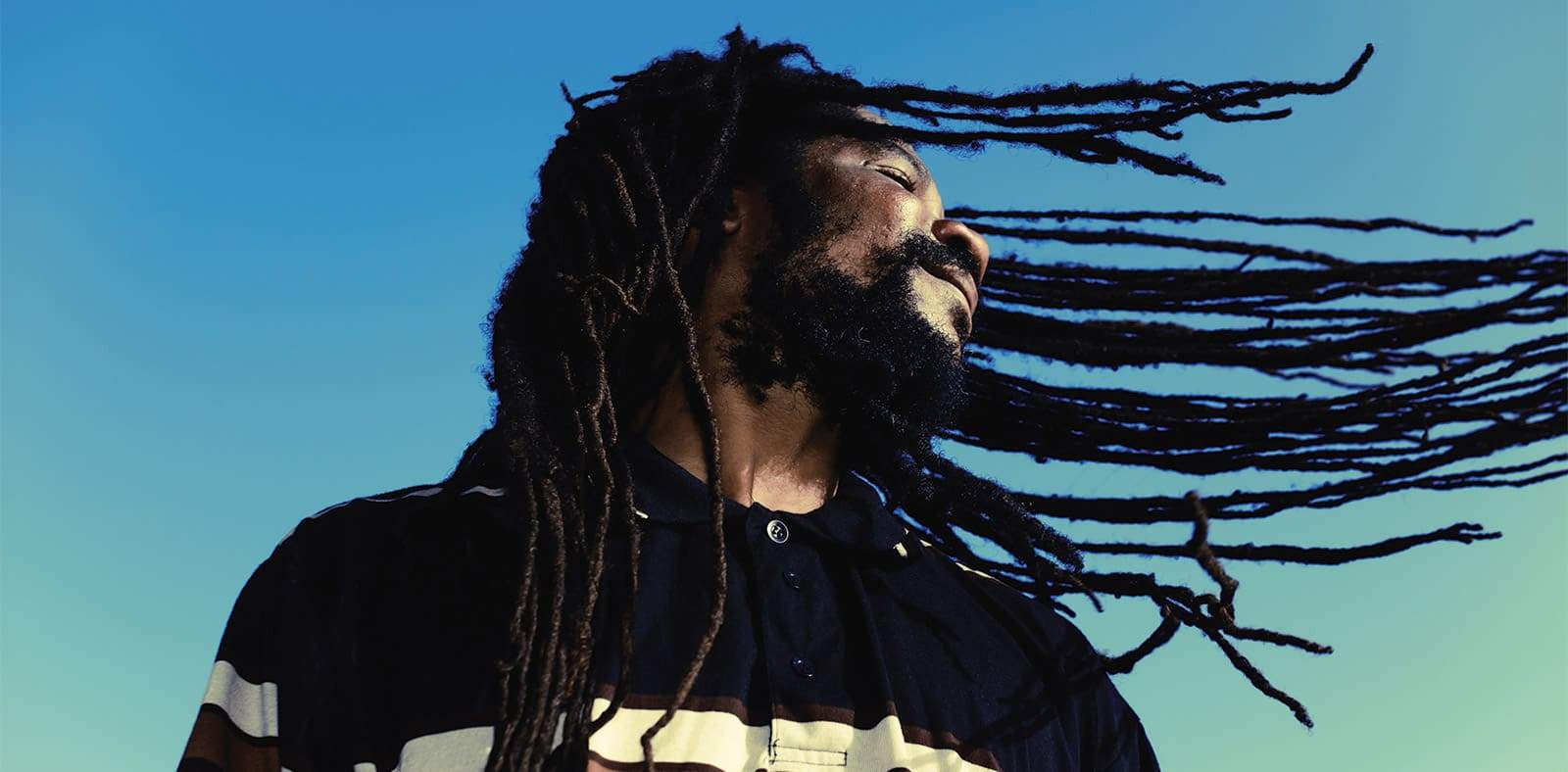 Homme-heureux-avec-les-dreadlocks-balancées-dans-les-airs