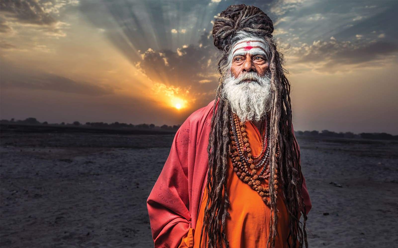 Sadhu portant des dreadlocks avec couché de soleil derriere lui