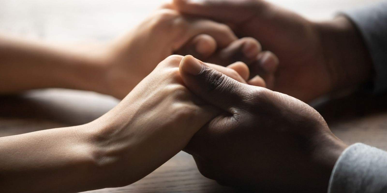 main d' un homme noir tenant les mains d'une femme blanche